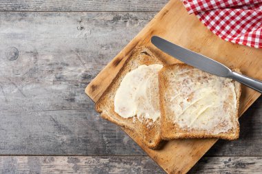 Tahta masada taze ekmek ve tereyağı dilimlenmiş. Üst Manzara. Özet Kopyala