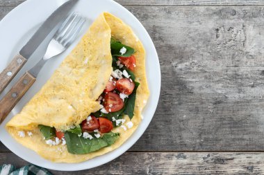 Domatesli omlet ve ahşap masada ıspanak.