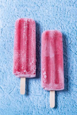 Mavi arka planda kırmızı çilekli dondurma.