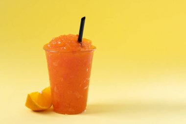 Sarı arka planda portakallı buzlu içecek. Boşluğu kopyala