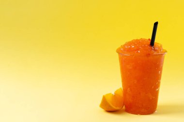 Sarı arka planda portakallı buzlu içecek. Boşluğu kopyala