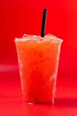 Kırmızı arka planda izole edilmiş kırmızı çilekli buzlu içecek. Boşluğu kopyala