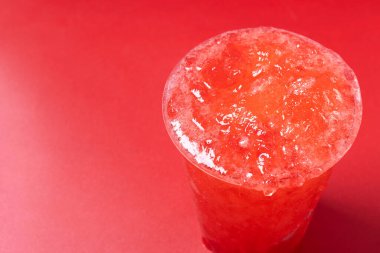 Kırmızı arka planda izole edilmiş kırmızı çilekli buzlu içecek. Boşluğu kopyala