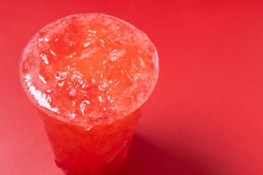 Kırmızı arka planda izole edilmiş kırmızı çilekli buzlu içecek. Boşluğu kopyala