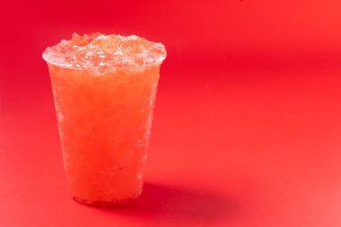 Kırmızı arka planda izole edilmiş kırmızı çilekli buzlu içecek. Boşluğu kopyala