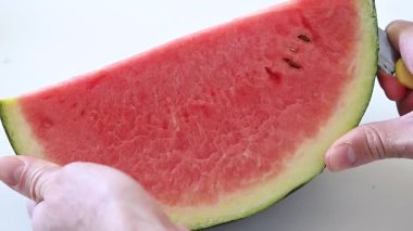 Adam elleri beyaz arka planda karpuz kesiyor.