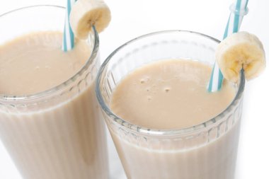 Beyaz arka planda izole edilmiş cam içinde taze ve sağlıklı muz suyu.