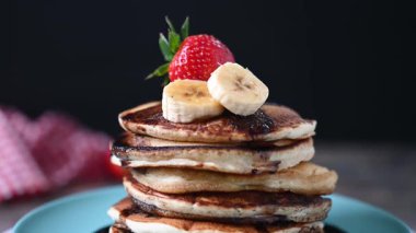 : Siyah arkaplanda dönen çikolatalı ve meyveli krepler.