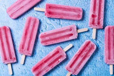 Mavi arkaplanda kırmızı çilekli dondurma deseni.