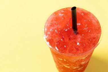 Sarı arka planda izole edilmiş kırmızı çilekli buzlu içecek. Boşluğu kopyala