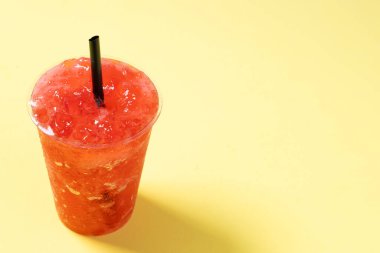 Sarı arka planda izole edilmiş kırmızı çilekli buzlu içecek. Boşluğu kopyala