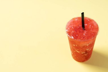 Sarı arka planda izole edilmiş kırmızı çilekli buzlu içecek. Boşluğu kopyala