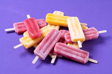 Kırmızı çilekli dondurma ve mor arka planda sarı buzlu şeker.