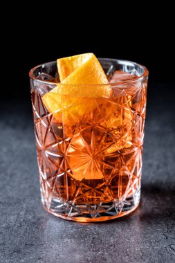 Siyah arka planda turuncuyla süslenmiş Americano kokteyli.