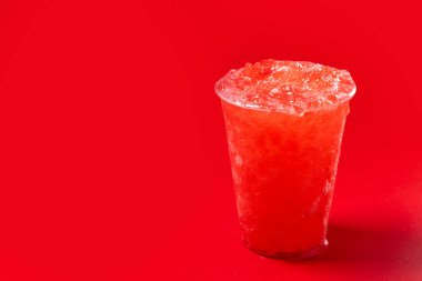 Kırmızı arka planda kırmızı çilekli buzlu içecek. Boşluğu kopyala