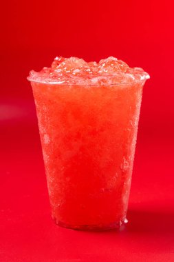 Kırmızı arka planda kırmızı çilekli içecek.