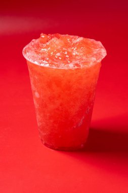 Kırmızı arka planda kırmızı çilekli içecek.