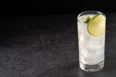 Siyah arka planda limonlu cin kokteyli. Boşluğu kopyala