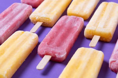 Kırmızı çilekli dondurma ve mor arkaplanda sarı buzlu şeker deseni.