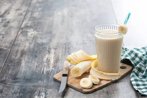 Tahta masada cam içinde taze ve sağlıklı muz suyu. Boşluğu kopyala