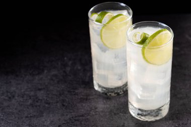 Siyah arka planda limonlu cin kokteyli. Boşluğu kopyala