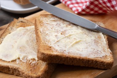 Tahta masada taze ekmek ve tereyağı dilimlenmiş.