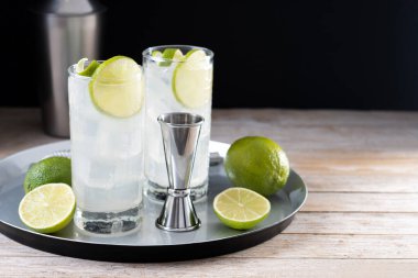 Limonlu cin kokteyli, ahşap masa ve siyah arka plan. Boşluğu kopyala