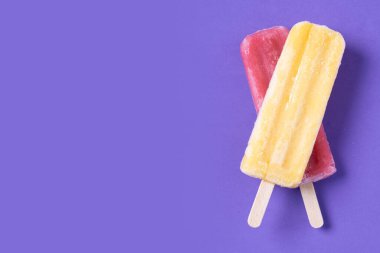 Mor arka planda kırmızı ve sarı buzlu şeker. Üst Manzara. Boşluğu kopyala