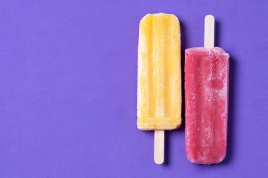 Mor arka planda kırmızı ve sarı buzlu şeker desenleri. Üst Manzara. Boşluğu kopyala