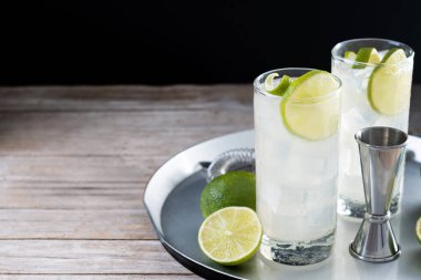 Limonlu cin kokteyli, ahşap masa ve siyah arka plan. Boşluğu kopyala