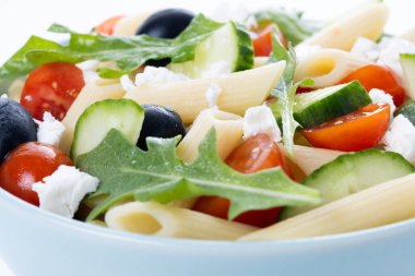 Akdeniz makarna salatası kasede taze sebzeler ve beyaz arka planda izole edilmiş otlar. Kapat.