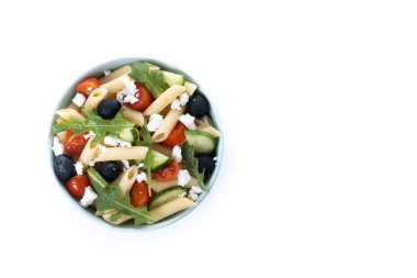 Akdeniz makarna salatası kasede taze sebzeler ve beyaz arka planda izole edilmiş otlar. Üst Manzara. Boşluğu kopyala