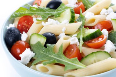 Akdeniz makarna salatası kasede taze sebzeler ve beyaz arka planda izole edilmiş otlar. Kapat.
