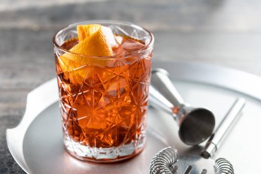 Amerikan kokteyli, ahşap masada turuncuyla süslenmiş.