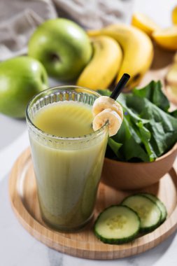 Tahta masalarda ıspanaklı, muzlu, elmalı ve limonlu yeşil smoothie.