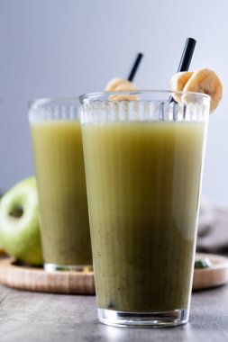 Ahşap masa üzerinde ıspanaklı, muzlu, elmalı ve limonlu yeşil smoothie.