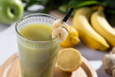 Beyaz mermer üzerinde ıspanaklı, muzlu, elmalı ve limonlu yeşil smoothie.