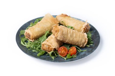 Çıtır sebzeler beyaz arka planda izole edilmiş seramik tabakta yuvarlanıyor.