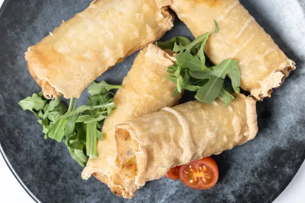 Çıtır sebzeler beyaz arka planda izole edilmiş seramik tabakta yuvarlanıyor. Üst görünüm