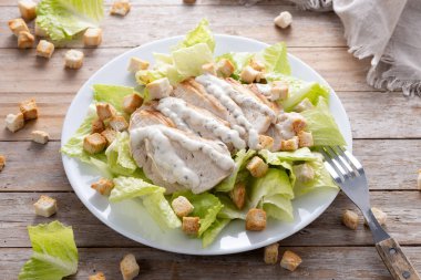  Tahta masada tavuklu gevrek Sezar salatası.