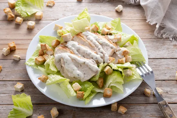  Tahta masada tavuklu gevrek Sezar salatası.