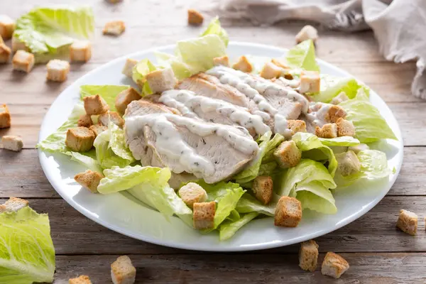  Tahta masada tavuklu gevrek Sezar salatası.