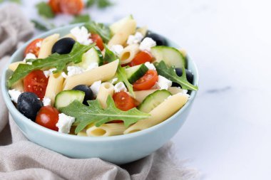 Akdeniz Makarna Salatası kasede Taze sebzeler ve beyaz mermer üzerinde bitkiler