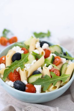 Akdeniz Makarna Salatası kasede Taze sebzeler ve beyaz mermer üzerinde bitkiler