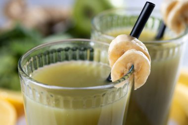 Beyaz mermer üzerinde ıspanaklı, muzlu, elmalı ve limonlu yeşil smoothie. Kapat.