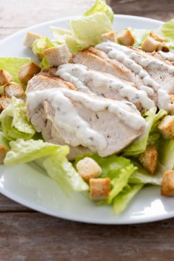 Tahta masada tavuklu gevrek Sezar salatası.