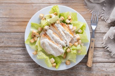 Tahta masada tavuklu gevrek Sezar salatası.