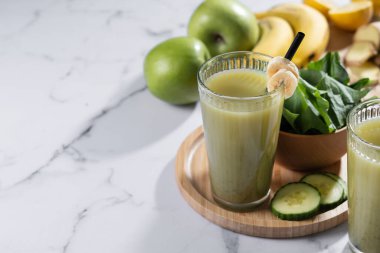 Beyaz mermer arka planda ıspanaklı, muzlu, elmalı ve limonlu yeşil smoothie. Boşluğu kopyala