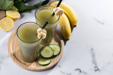 Beyaz mermer üzerinde ıspanaklı, muzlu, elmalı ve limonlu yeşil smoothie. Boşluğu kopyala