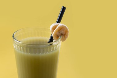 Sarı arka planda ıspanaklı, muzlu, elmalı ve limonlu yeşil smoothie. Boşluğu kopyala